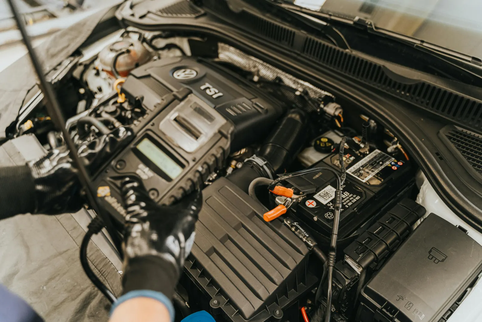 Technicien testant une batterie 12V avec un testeur numérique